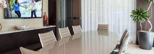 Interior view of resident conference room at AMLI River Oaks apartments with large table and eight chairs and large screen TV