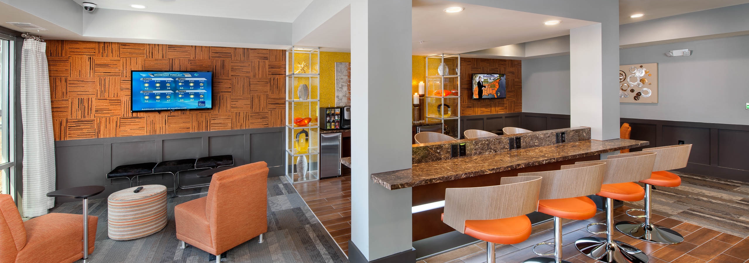 AMLI Piedmont Heights colorful clubroom showcasing counter space with barstools and seating area looking at large TV on wall