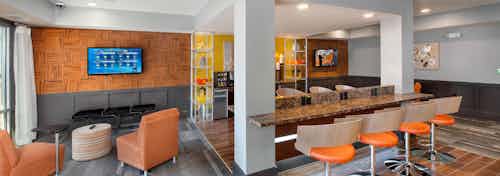 AMLI Piedmont Heights colorful clubroom showcasing counter space with barstools and seating area looking at large TV on wall