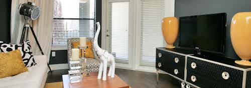 Interior view of AMLI at Escena apartment living room with couch, large screen TV and large window and door to patio