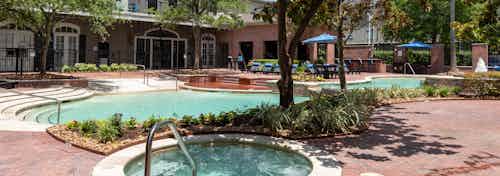 Heated spa, swimming pool and clubhouse with landscaping and trees at AMLI Memorial Heights apartment building