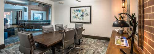 Interior of conference room at AMLI Las Colinas apartment building with wood table and six chairs and artwork on walls