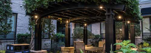 Nighttime view of verandah covered with greenery at AMLI Las Colinas apartment building with table and chairs and lights