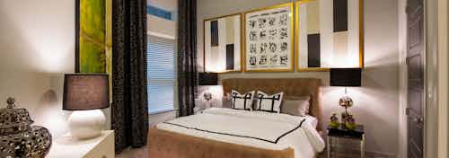 AMLI Uptown apartment bedroom with bed, two nightstands with lamps and dresser and window with blinds and curtains