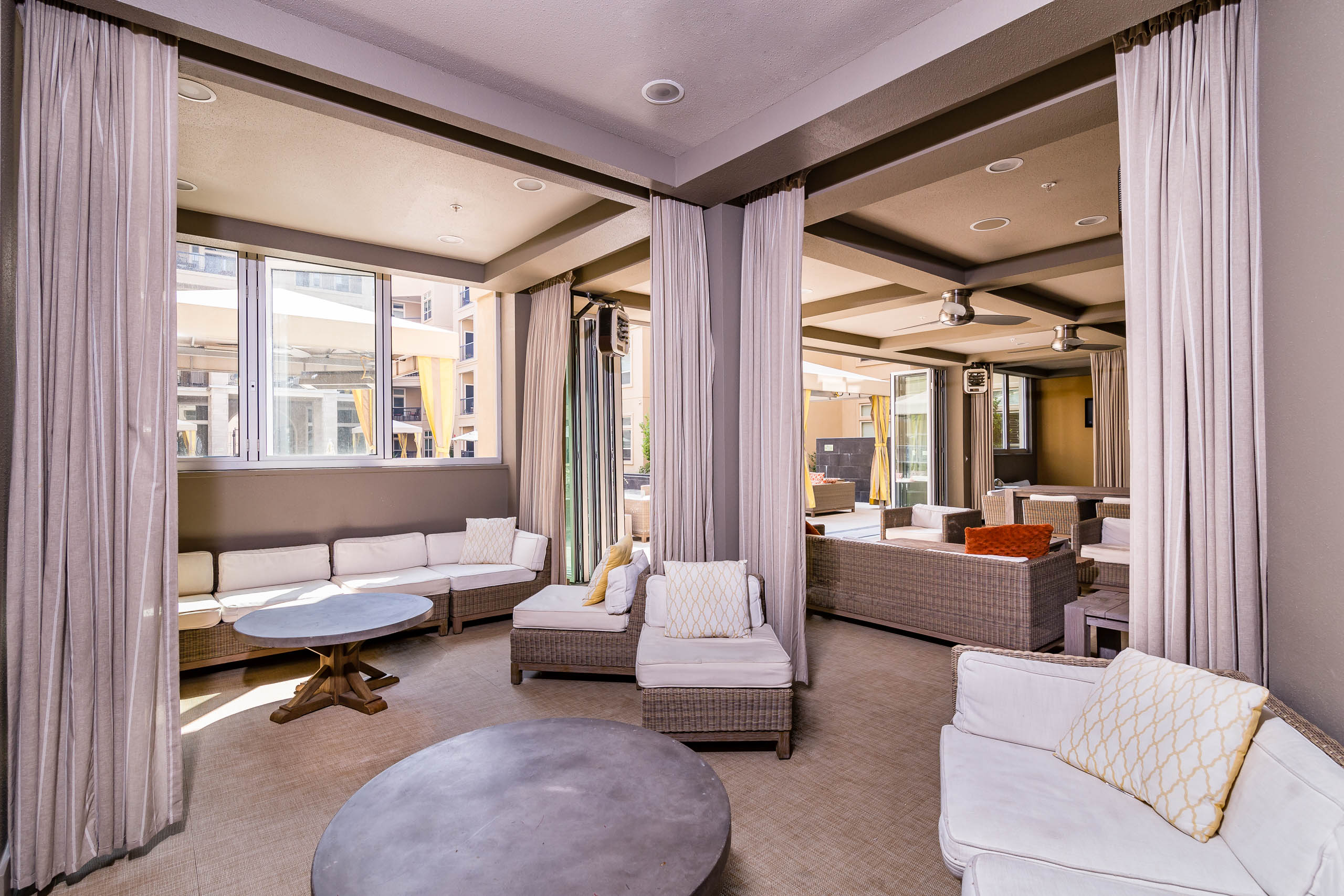 Daytime interior of poolside clubhouse with stylish lounge seating and room divider curtains at AMLI RidgeGate apartments