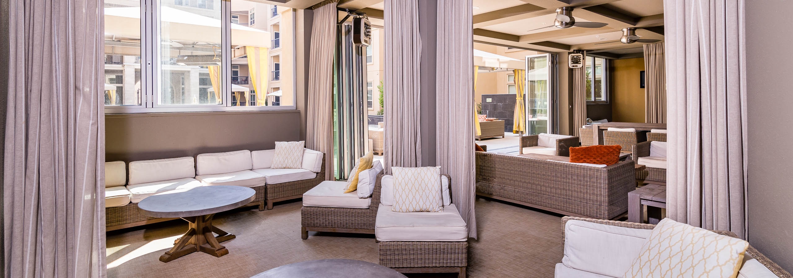 Daytime interior of poolside clubhouse with stylish lounge seating and room divider curtains at AMLI RidgeGate apartments