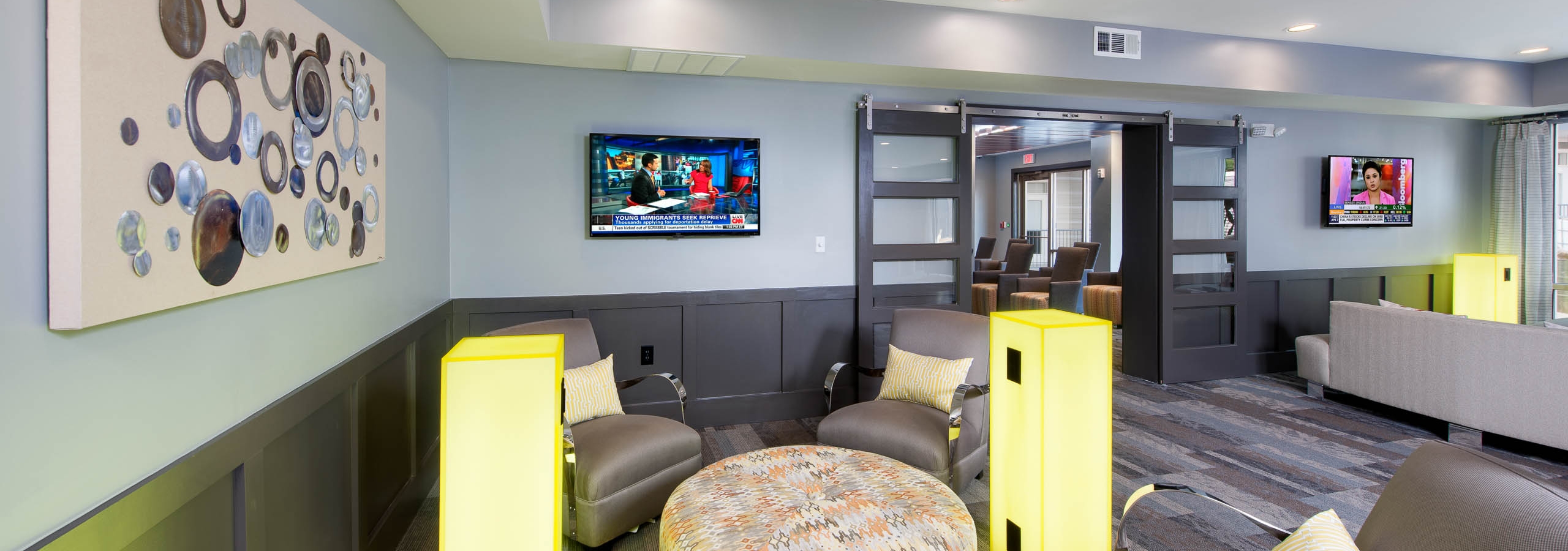 Clubroom at AMLI Piedmont Heights with multiple areas of seating next to large neon electrical ports to charge electronics