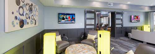 Clubroom at AMLI Piedmont Heights with multiple areas of seating next to large neon electrical ports to charge electronics