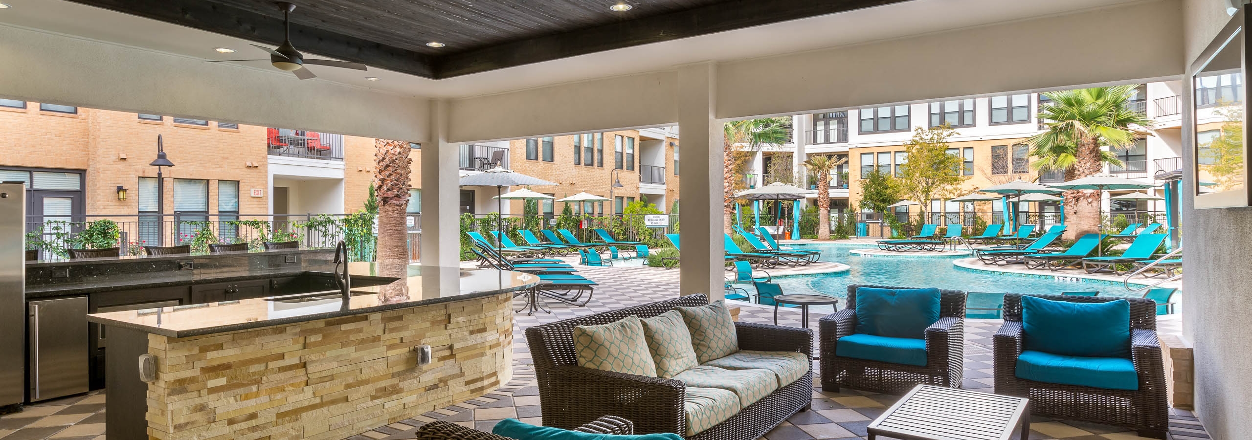 Daytime view of AMLI Campion Trail cabana with comfortable seating and serving bar overlooking pool area with lounges
