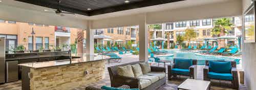 Daytime view of AMLI Campion Trail cabana with comfortable seating and serving bar overlooking pool area with lounges