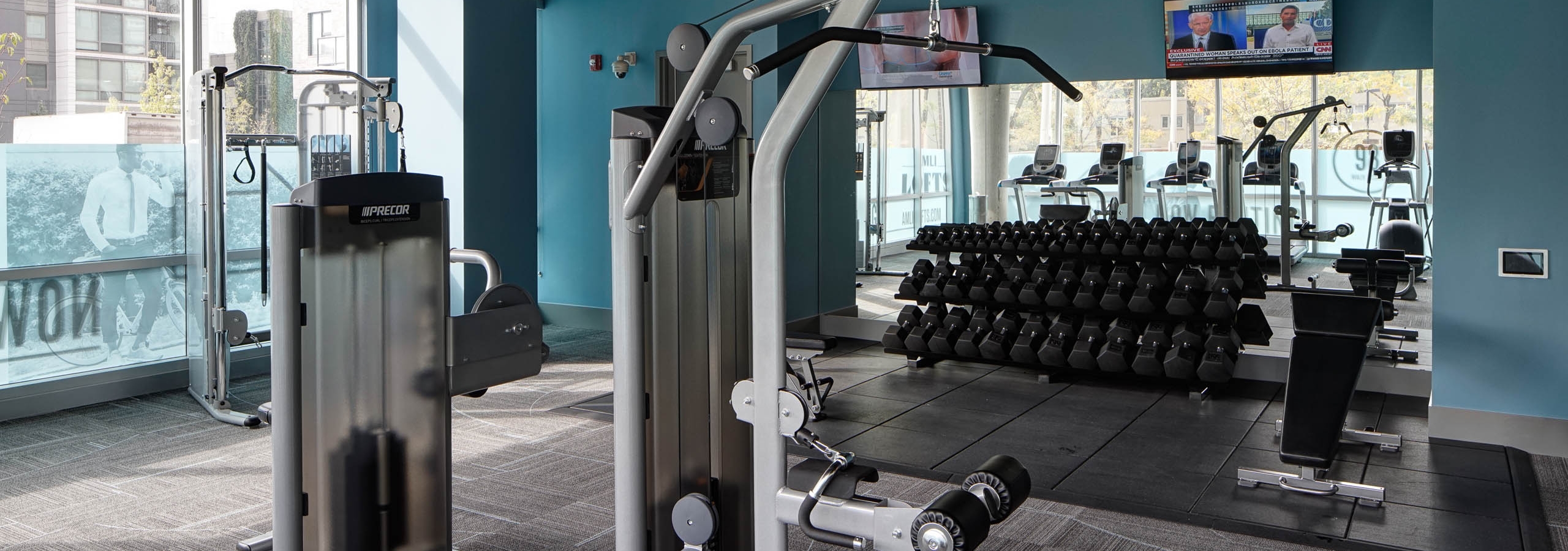 An alternative interior view of the fitness center at AMLI Lofts which has teal walls and an area designated for weights