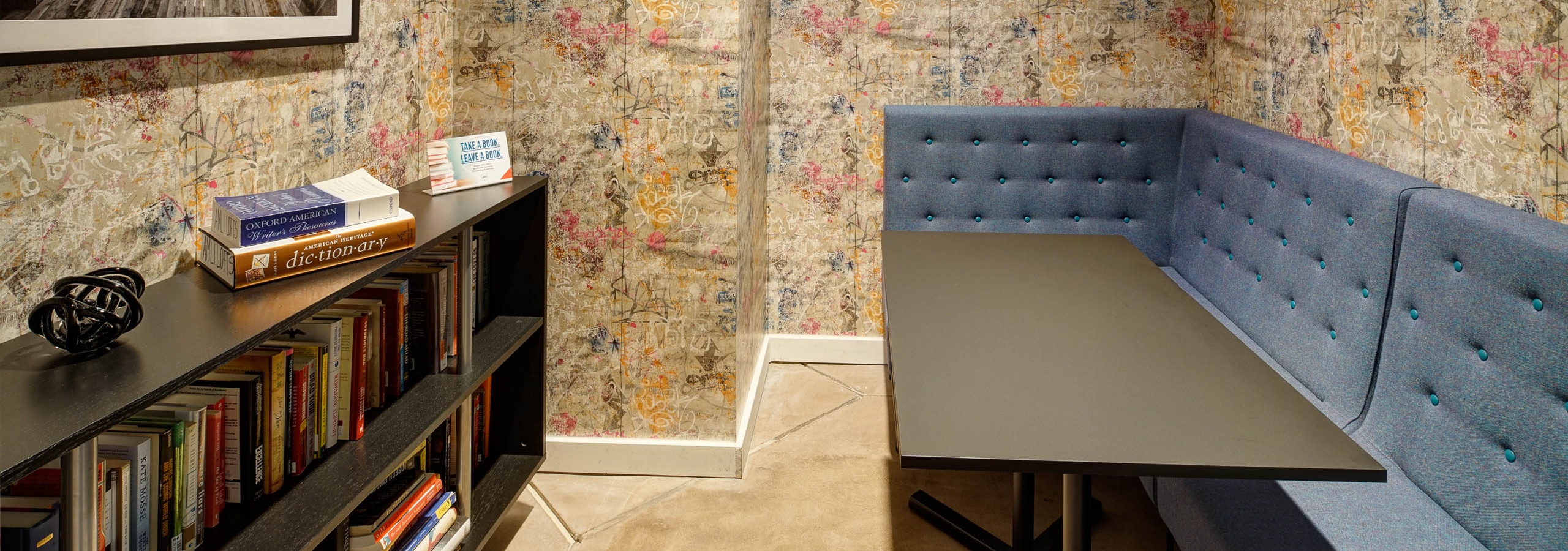 Interior view of the library at AMLI Lofts which has colorful walls with a horizontal bookshelf and a nook area for reading