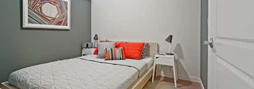 Apartment bedroom at AMLI South Lake Union with a queen-sized bed in the corner and bedside table with a lamp.