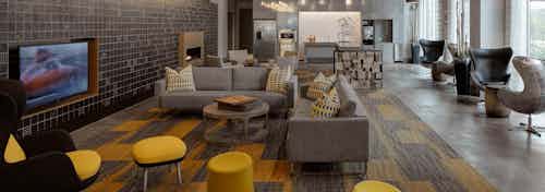 The resident clubroom at AMLI Lofts which has multiple seating areas and a large TV with vibrant yellow accents in the decor