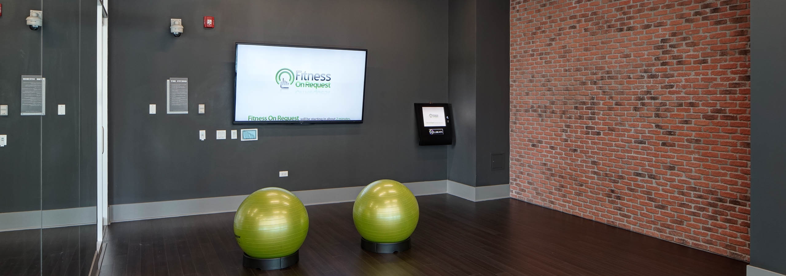 Studio with fitness on demand at AMLI Lofts with wide open space for exercise as well as a flat screen TV and exercise balls