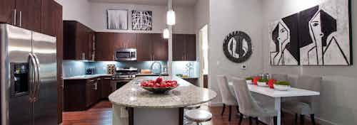 AMLI Uptown apartment island kitchen with granite countertops and stainless steel appliances and dark brown wood cabinetry