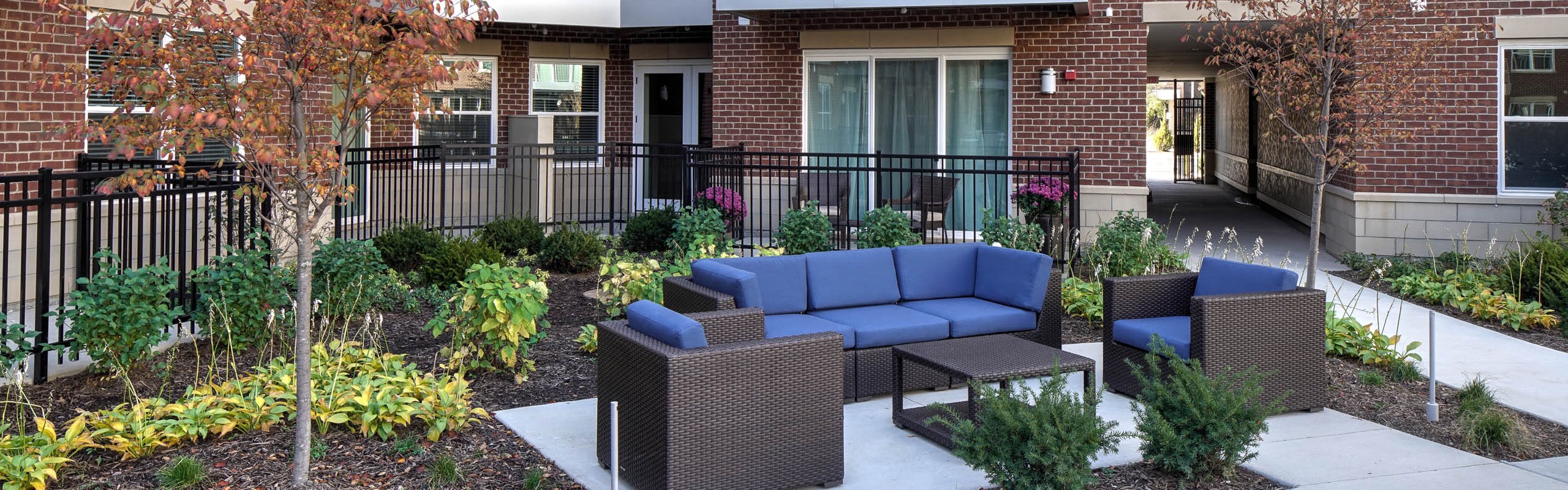 AMLI Deerfield outdoor courtyard living room furniture with couch and two chairs and table with landscaped trees and plants