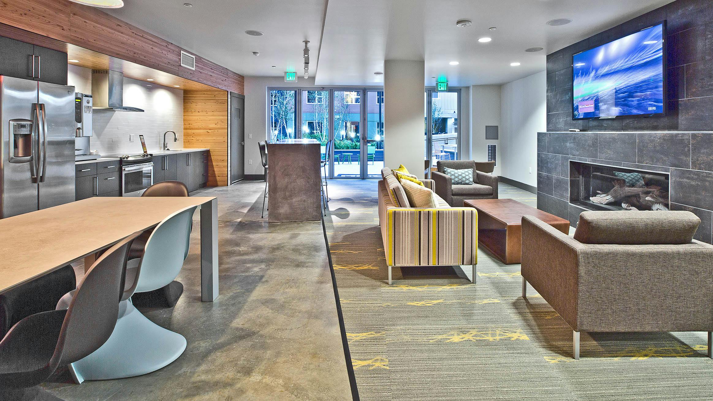 Resident lounge at AMLI Mark 24 apartments with fireplace, seating, a TV and resident kitchen area
