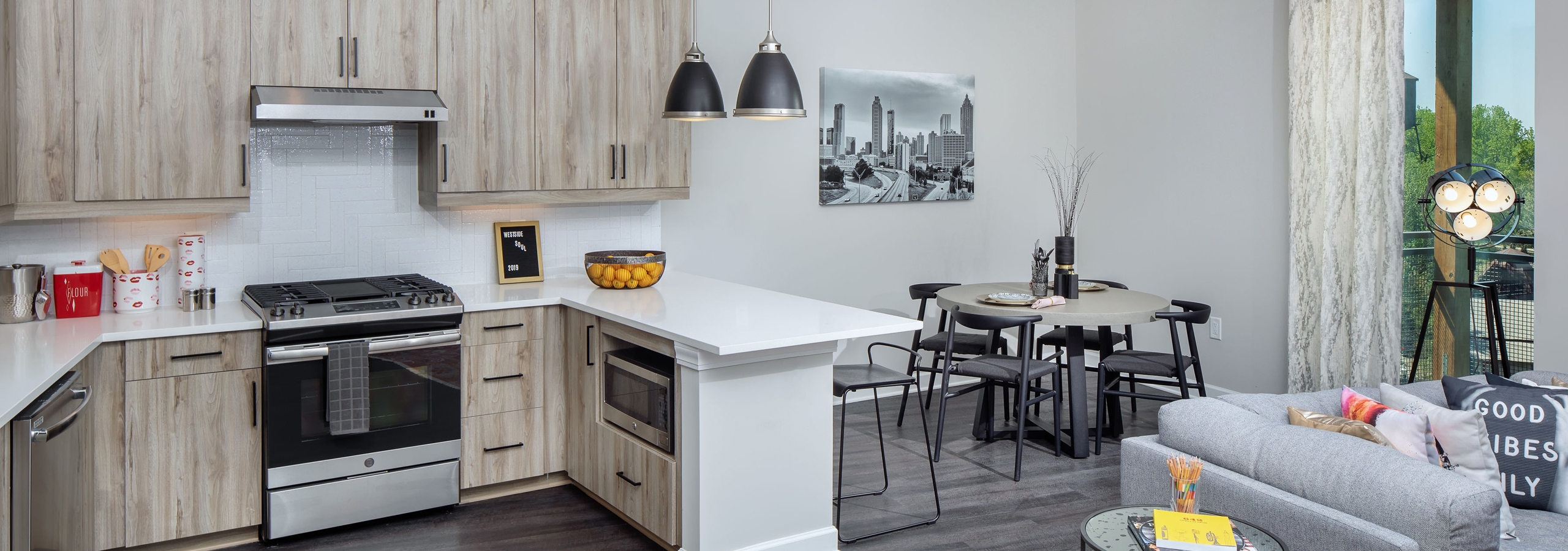 AMLI Westside apartment kitchen with light wooden cabinets and stainless steel appliances with white countertops