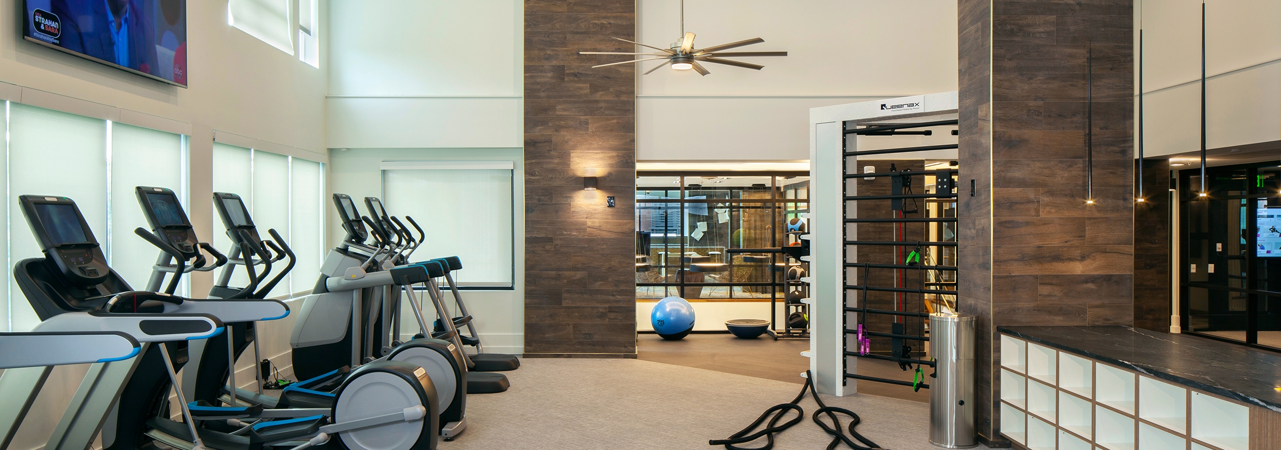 Fitness center at AMLI Riverfront Green apartments with multiple treadmills and elliptical machines with overhead fans