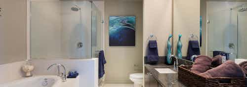 Interior view of AMLI Design District apartment bathroom with granite countertop, oval garden tub and glass shower