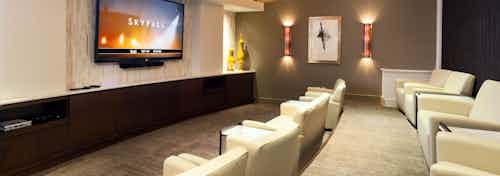 Interior view of private screening room with 80” HDTV and beige leather club seating at AMLI River Oaks apartment building