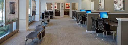 The leasing office at AMLI 900 which features neutral finishes and contains multiple wooden desks with computers and chairs