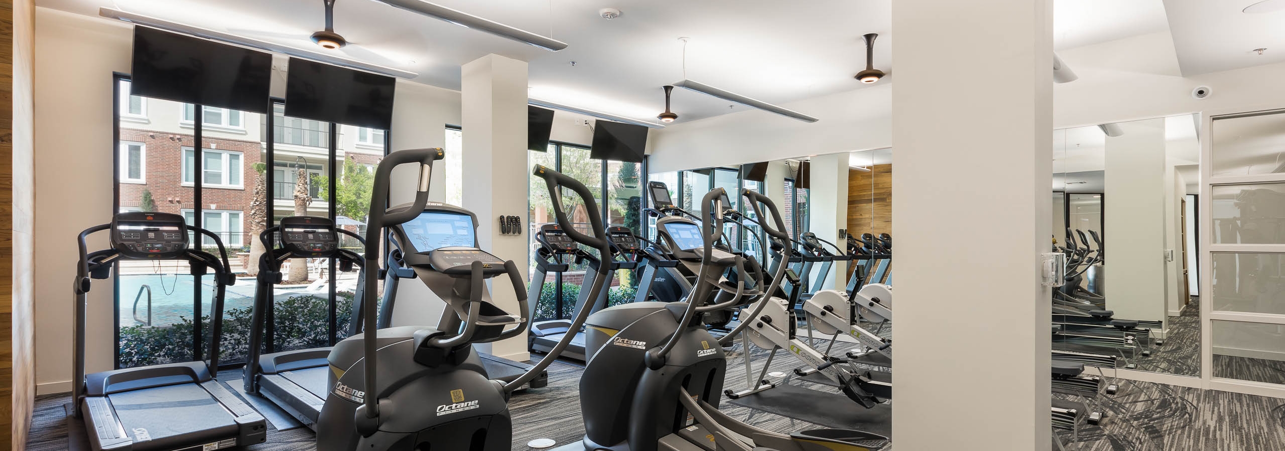 AMLI Frisco Crossing fitness center with treadmills and other cardio machines and mounted TVs and ceiling fans above