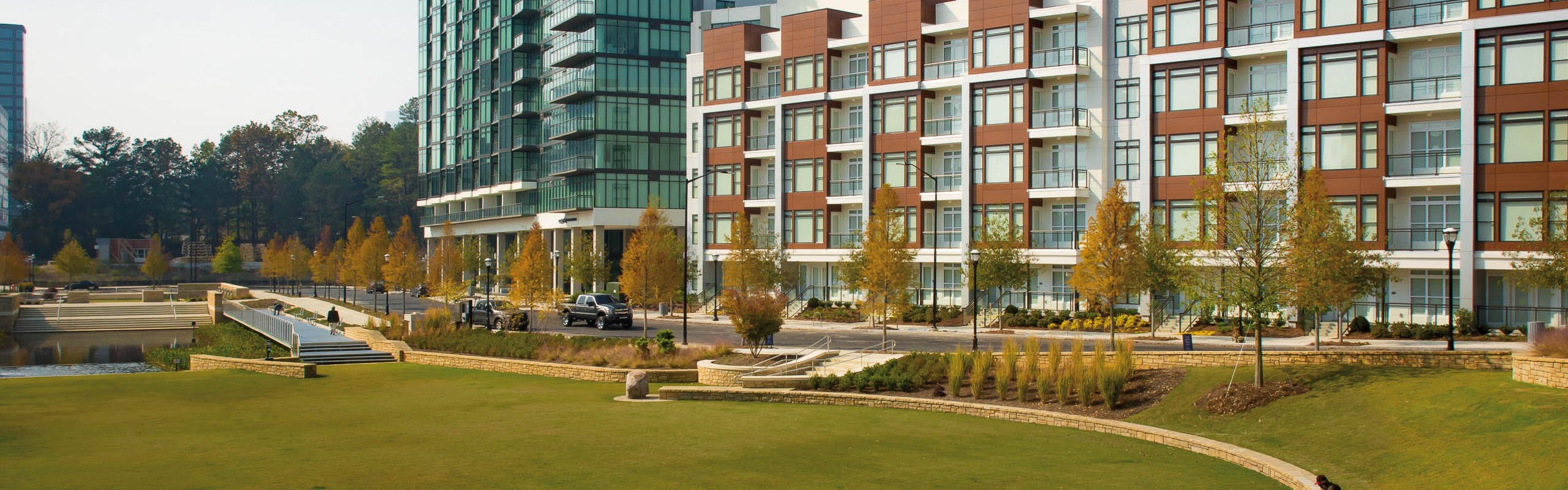 Exterior of the AMLI 3464 building in daylight with autumn trees lining the pavement and vibrant grass on the alternate side