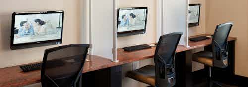 Interior of business center at AMLI at Escena apartment building with three computer stations and chairs