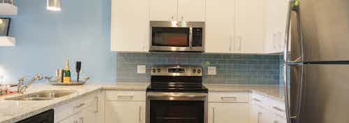 A kitchen of an apartment at AMLI Sawgrass Village with a stainless steel microwave nested in white cabinets above an oven