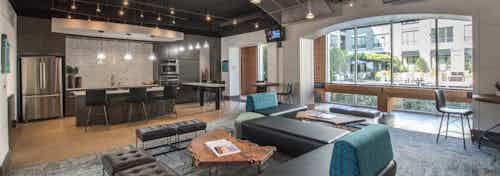 Interior view of resident lounge at AMLI Las Colinas apartment building with resident kitchen and game tables and seating
