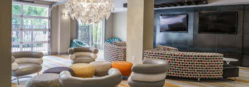 Interior view of club room at AMLI Sawgrass Village with ample colorful seating, big screen TVs, modern décor and pool view