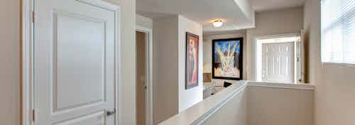 Upstairs townhome hallway at AMLI Memorial Heights apartments with window and two pieces of colorful artwork on walls