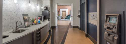 Interior of java bar area at AMLI Las Colinas apartment building with sink, dark wood cabinets and hallway looking into lobby