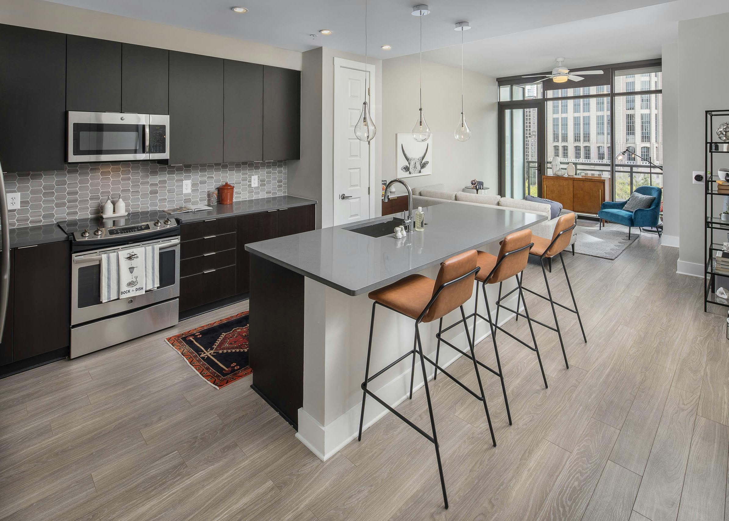 Kitchen at AMLI Arts Center with black cabinets and sleek grey countertops with a light grey patterned backsplash and island