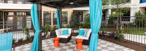Daytime view of AMLI Campion Trail personal curtained cabana with comfortable seating and two small orange tables