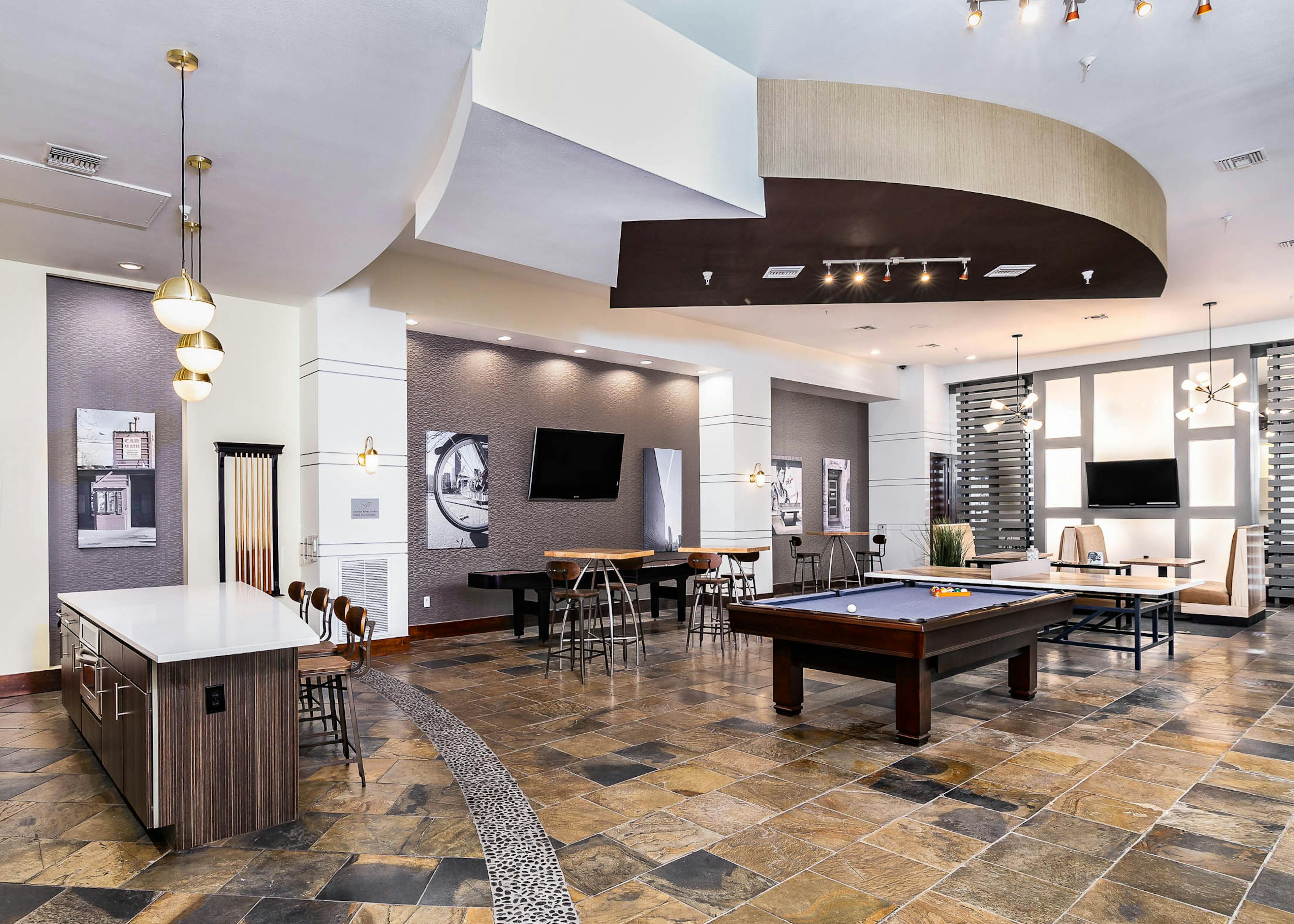 Interior view of the club room at AMLI Park Avenue apartments with a pool table and multiple seating areas and wall art work