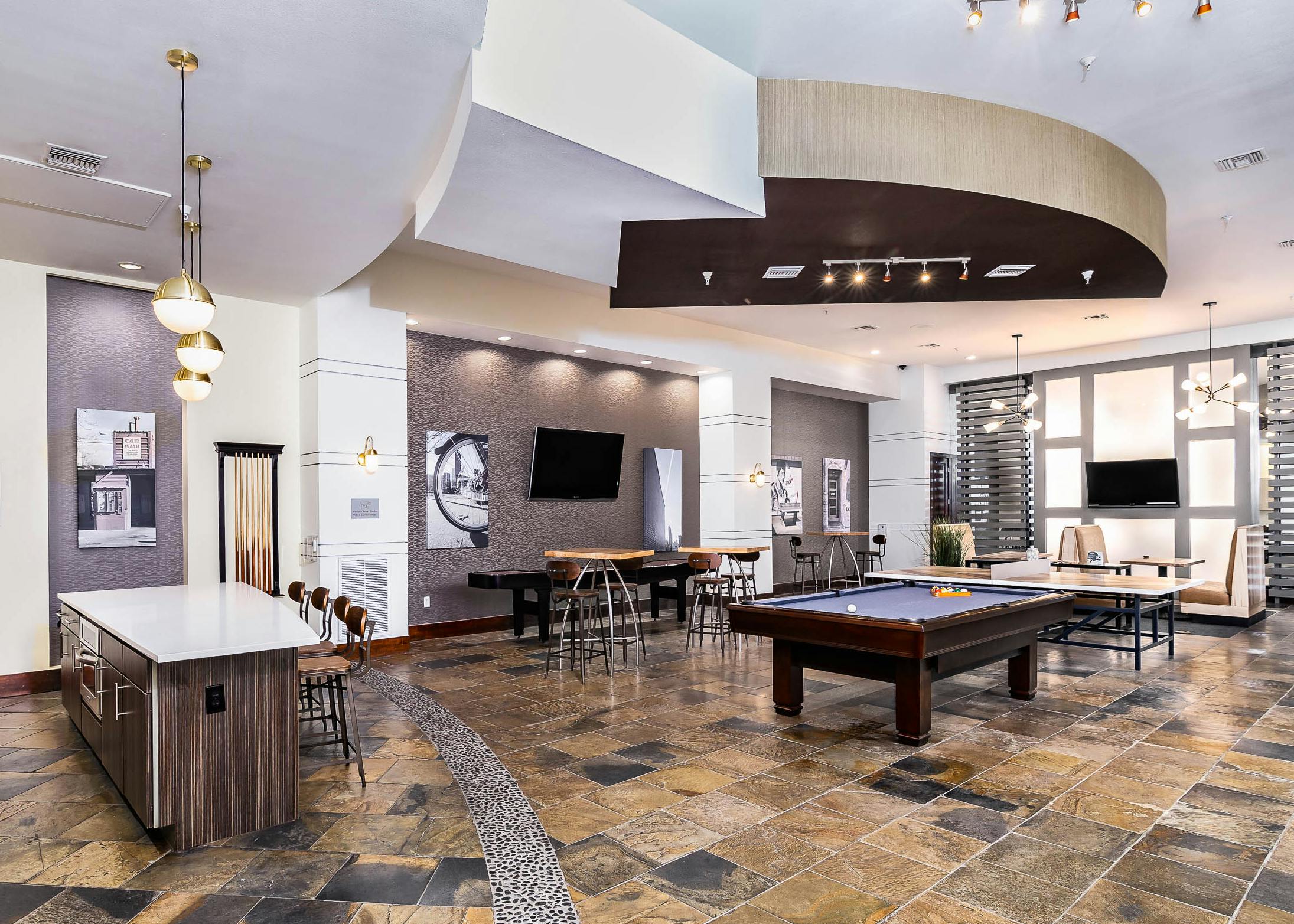 Interior view of the club room at AMLI Park Avenue apartments with a pool table and multiple seating areas and wall art work
