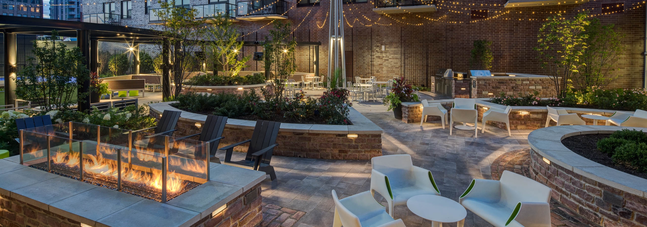 Exterior view of the courtyard lounge at the AMLI Lofts apartment community at night with city buildings visible in the back