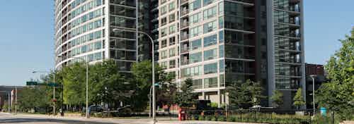 Daytime view of the AMLI 900 apartment community building which consists mostly of glass windows with neutral brick touches