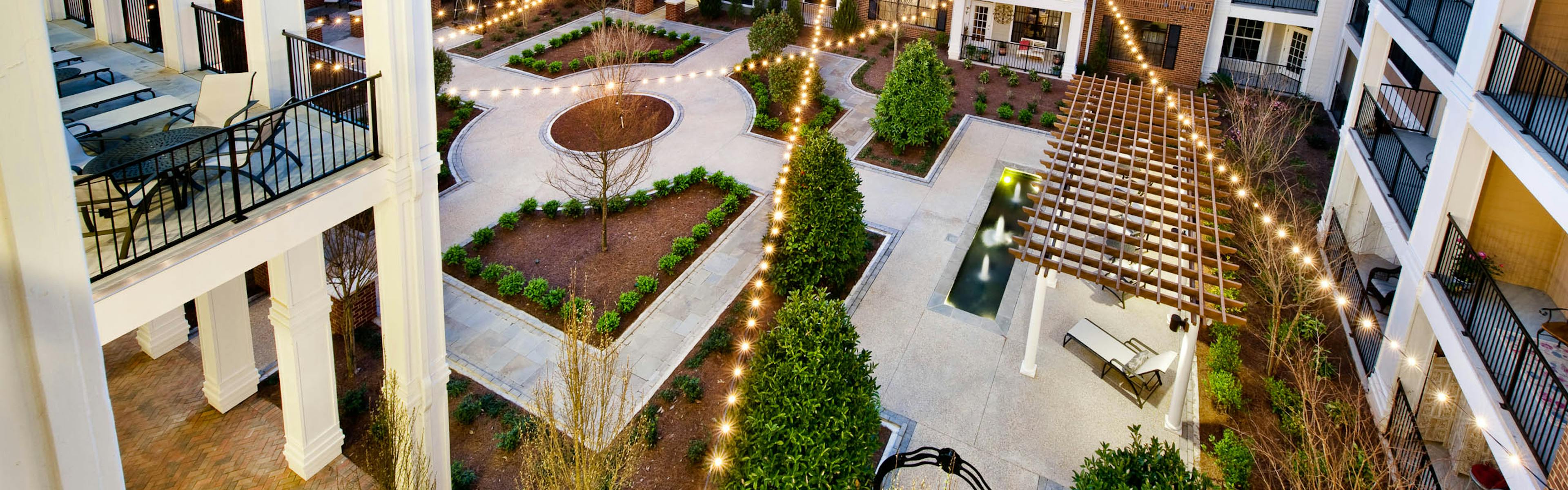AMLI North Point courtyard with balconies and string lights above pavement for walking which is lined with pristine landscape