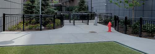 Exterior view of the gated dog run with artificial turf at the AMLI Lofts apartment community in the bright day time