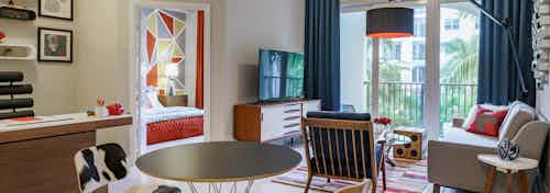 An AMLI Sawgrass Village apartment living area with a cow-patterned dining set and living room furniture and TV beyond