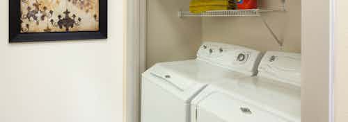 Interior view of AMLI Las Colinas apartment with side-by-side full-size washer and dryer and shelving above