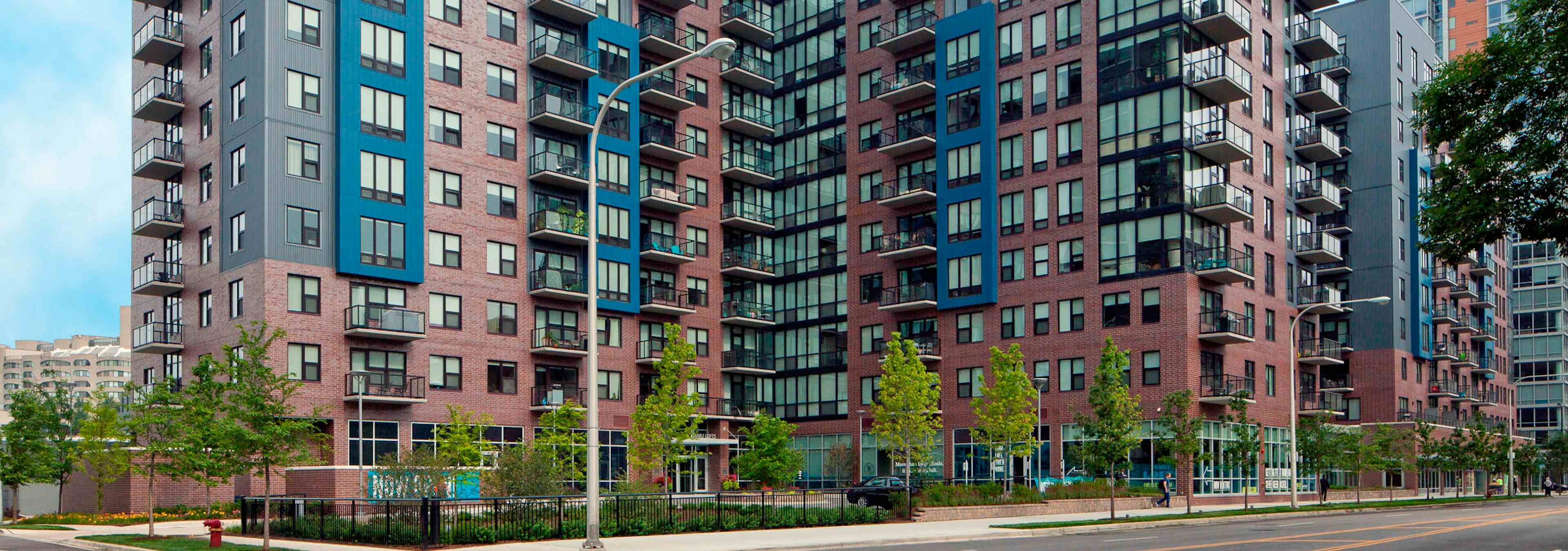 Daytime view of the AMLI Lofts apartment community building which has a pale red brick facade with vibrant blue accents