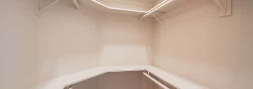 Interior view of large walk-in closet with hanging space and rows of shelves in AMLI Las Colinas apartment bedroom