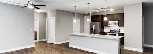 Interior of AMLI Frisco Crossing apartment kitchen with espresso cabinetry, tile backsplash and stainless steel appliances