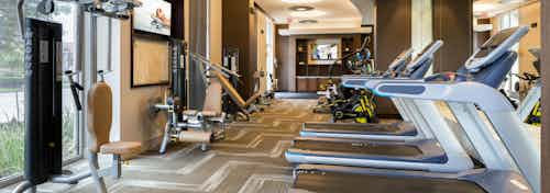 Fully equipped fitness center at AMLI River Oaks apartment building with strength machines at left and tread mills at right