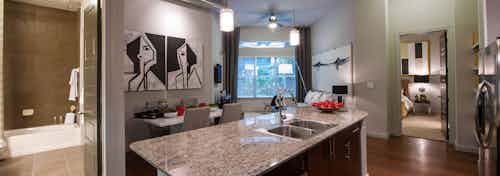 Interior view of AMLI Uptown apartment from granite island with glimpse into bathroom and dining and living areas and bedroom